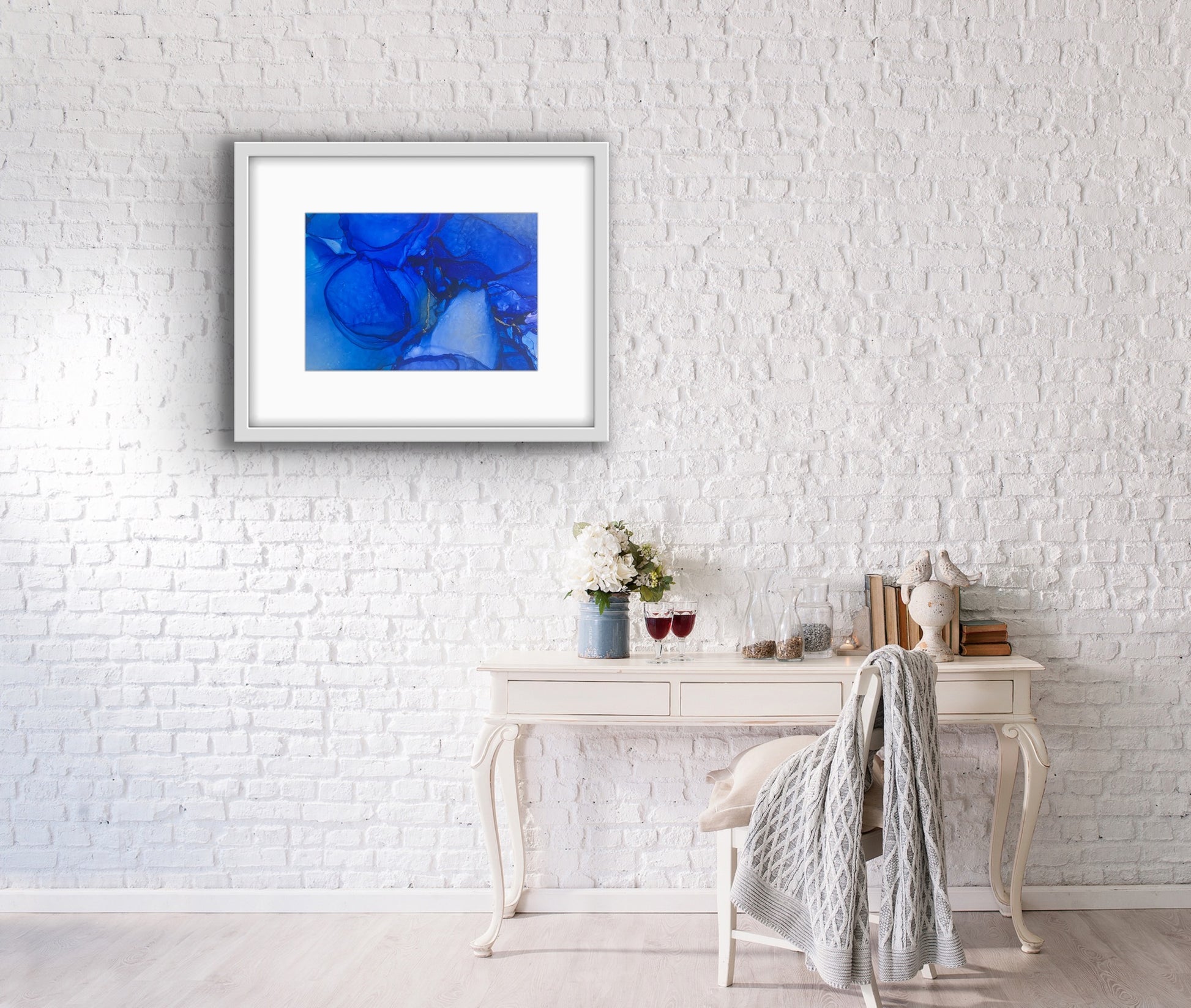 Blue Drift by Ludwina Orchard – alcohol ink painting on polypropylene displayed above a white shabby-chic console table against a white brick wall
