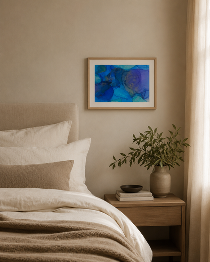 Cerulean by Ludwina Orchard – alcohol ink painting displayed in a cosy bedroom with white linen bedding and a wooden nightstand with greenery