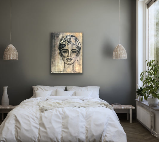 Earth Goddess by Ludwina Orchard – acrylic portrait painting on textured background displayed above a bed in a calm neutral bedroom with pendant lights